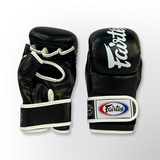 כפפות MMA Fairtex מונחות על משטח אימון כחלק מציוד אגרוף מקצועי למתאמנים--שחור אפור